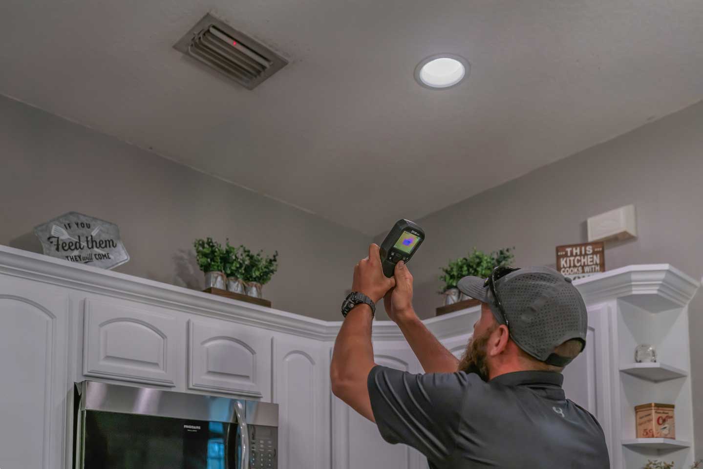 Inspector using a thermal camera to examine an interior ceiling